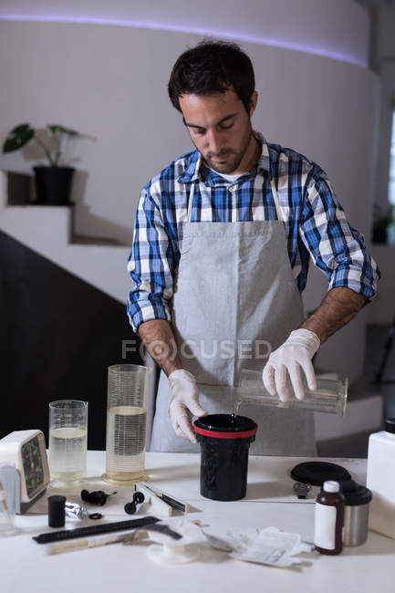 Fotógrafo masculino limpando uma tampa da lente com líquido no estúdio de fotografia — Fotografia de Stock