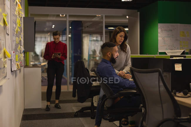 Коллеги обсуждают за компьютером в офисе — стоковое фото