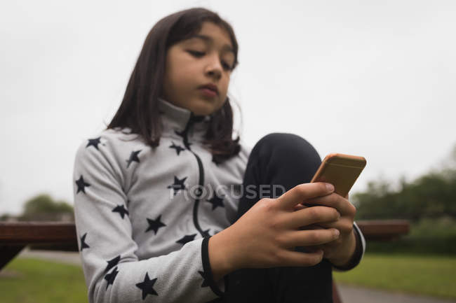 Jeune fille à l'aide de téléphone mobile au jardin — Photo de stock
