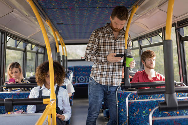 Умный мужчина, пользующийся мобильным телефоном во время поездки в современном автобусе — стоковое фото