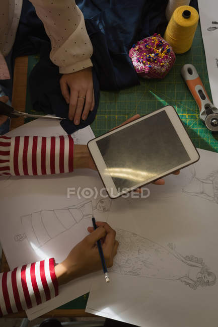 Primer plano de los diseñadores de moda dibujando un boceto usando tableta digital en el estudio de moda - foto de stock