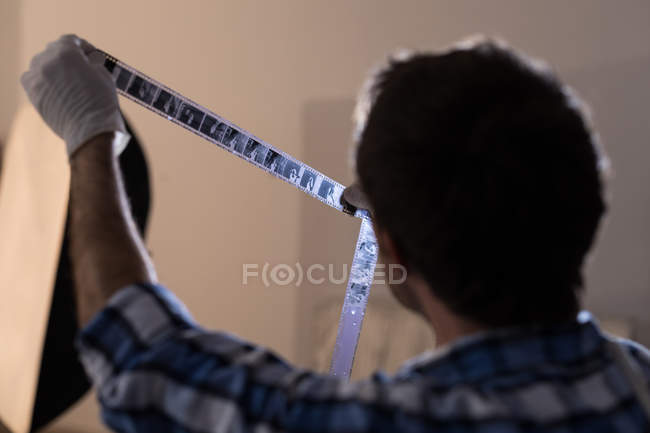 Fotógrafo masculino checando filmstrip câmera no estúdio de fotos — Fotografia de Stock