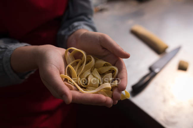 Tagliatelle in der Hand, während Bäcker Tagliatelle in der Bäckerei zubereitet — Stockfoto