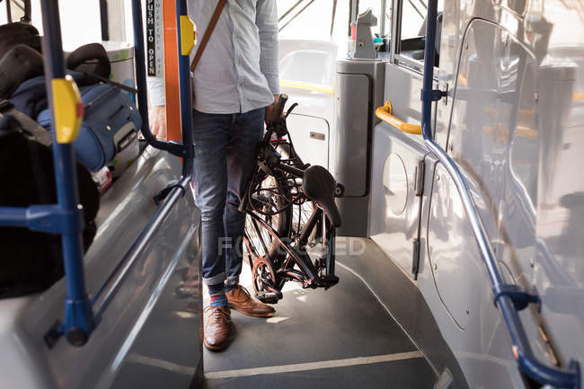 Low section of male commuter with folding bicycle entering in modern bus — Stock Photo