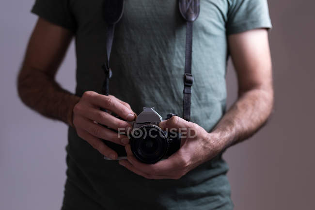 Mid section of male photographer standing with digital camera — Stock Photo