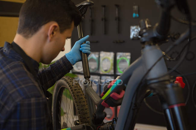 Junger Mann hält Fahrrad in Werkstatt — Stockfoto