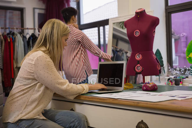 Designer de moda bonita usando laptop no estúdio de moda — Fotografia de Stock