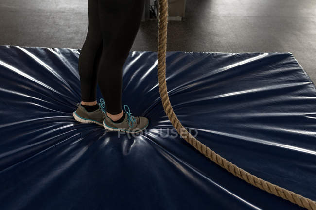 Baixa seção de mulher fazendo exercício de escalada de corda no ginásio de fitness — Fotografia de Stock