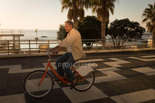 Senior uomo in bicicletta sul lungomare in una giornata di sole — Foto stock