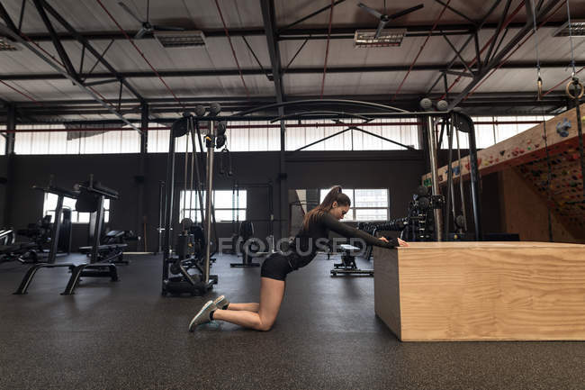 Mujer en forma haciendo ejercicio de estiramiento en el gimnasio - foto de stock