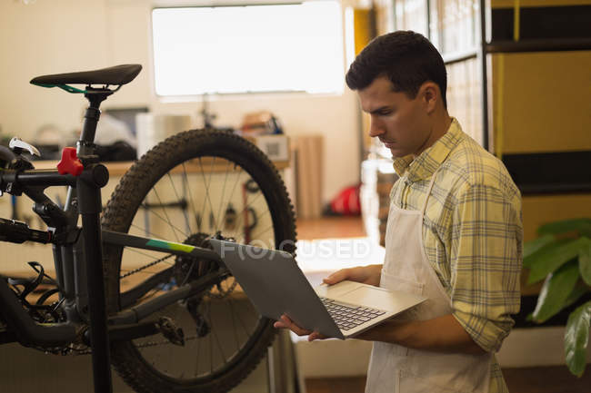 Hombre joven usando portátil en el taller - foto de stock