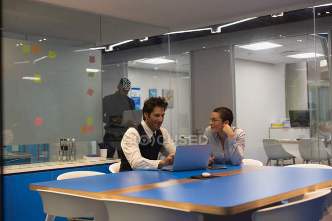 Деловые коллеги обсуждают за ноутбуком в офисе — стоковое фото