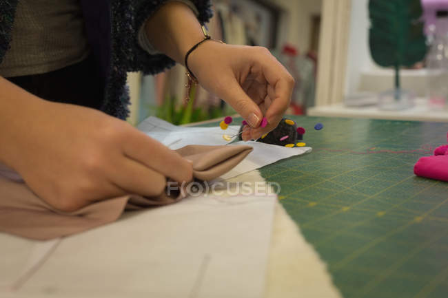 Close-up de designer de moda pinning em tecido no estúdio de moda — Fotografia de Stock