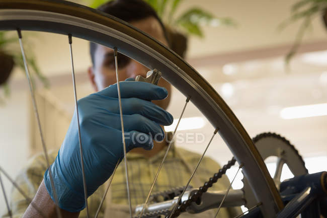Primer plano del hombre fijación de cuerdas de rueda de bicicleta en el taller - foto de stock
