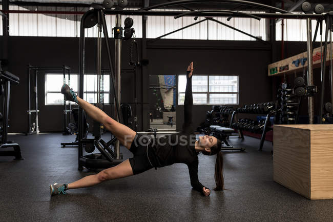 Beautiful woman doing side plank exercise in fitness studio — Stock Photo