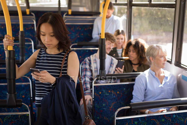 Viajante feminino usando telefone celular enquanto viaja em ônibus moderno — Fotografia de Stock