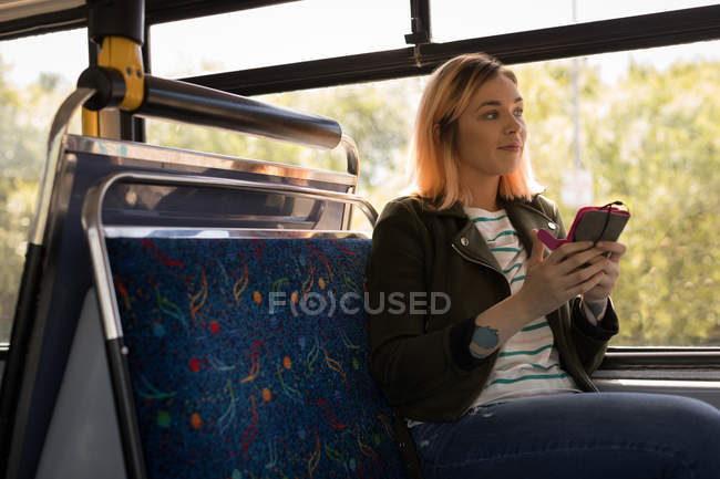 Жінка-комісарка використовує мобільний телефон під час подорожі в сучасному автобусі — стокове фото