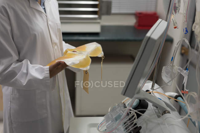 Technicien de laboratoire tenant des sacs plasma dans une banque de sang — Photo de stock