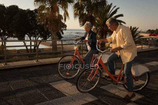 Casal sênior andar de bicicleta no passeio em um dia ensolarado — Fotografia de Stock