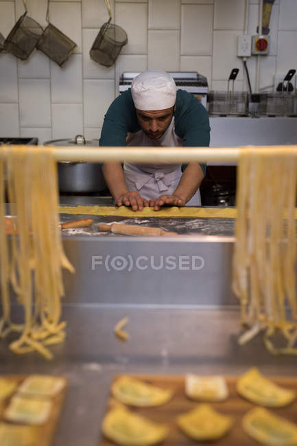 Cocinero masculino atento preparando pasta en panadería - foto de stock