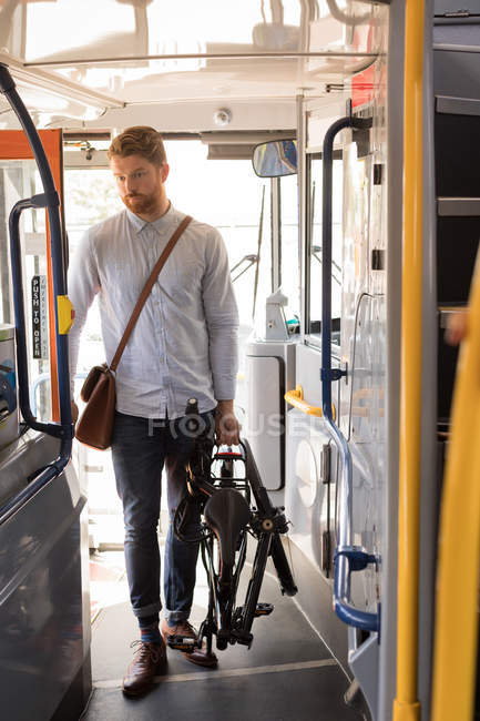 Homem inteligente com bicicleta dobrável entrando em ônibus moderno — Fotografia de Stock