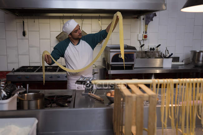 Мужчина пекарь готовит макароны в пекарне — стоковое фото