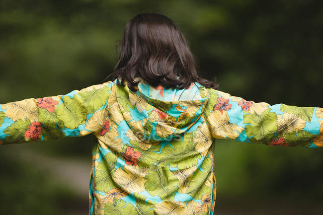 Visão traseira da menina com os braços em pé na floresta — Fotografia de Stock
