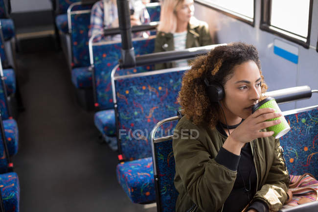 Jovem viajante do sexo feminino tomando café enquanto viaja em ônibus moderno — Fotografia de Stock