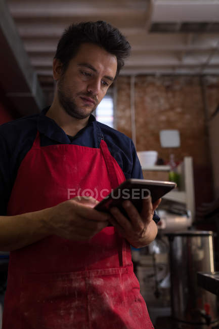 Boulanger masculin utilisant une tablette numérique dans la boulangerie — Photo de stock