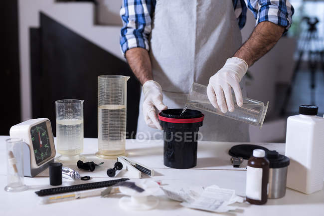 Мужчина-фотограф чистит крышку объектива жидкостью в фотостудии — стоковое фото