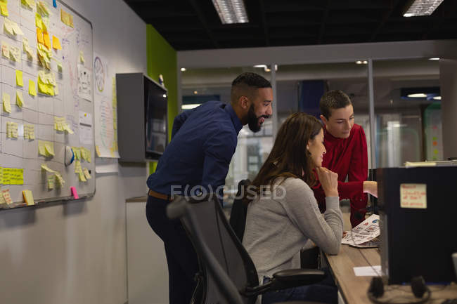 Колеги обговорюють комп'ютер в офісі — стокове фото