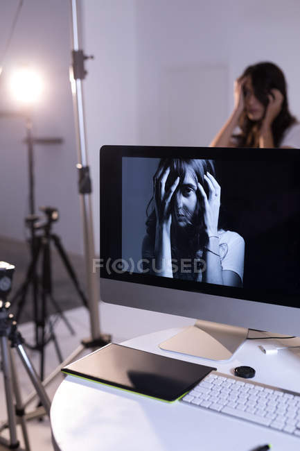Modèle féminin posant sur écran d'ordinateur en studio photo — Photo de stock