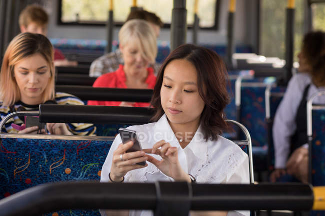 Женщина пригородная с помощью мобильного телефона во время путешествия в автобусе — стоковое фото