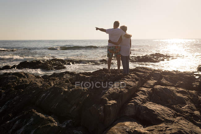 Rückansicht eines älteren Mannes, der auf einem Felsen in der Nähe des Meeres steht — Stockfoto
