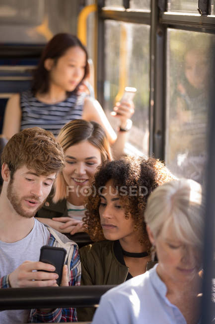 Друзья пользуются мобильным телефоном во время поездки в современном автобусе — стоковое фото