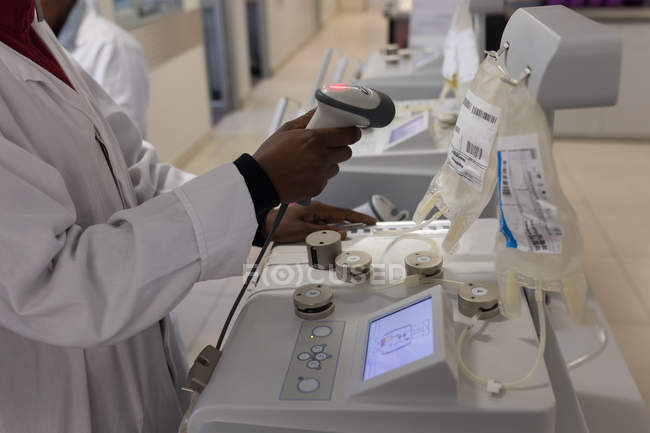 Técnico de laboratorio escaneando código de barras de bolsas de plasma en banco de sangre - foto de stock