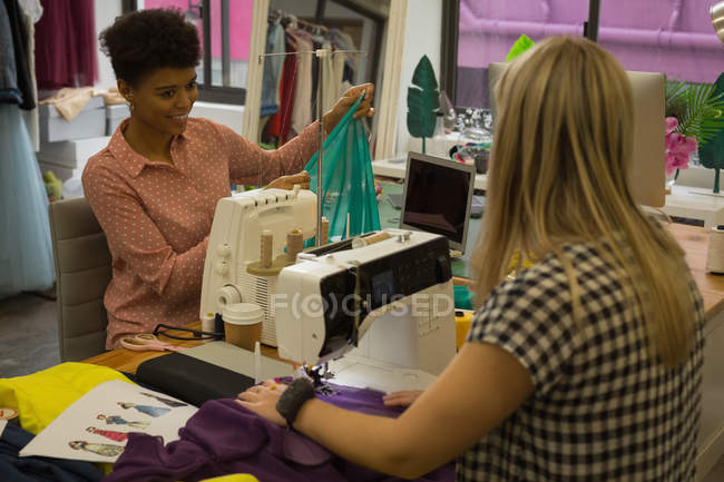 Diseñadores de moda usando máquina de coser en estudio de moda - foto de stock