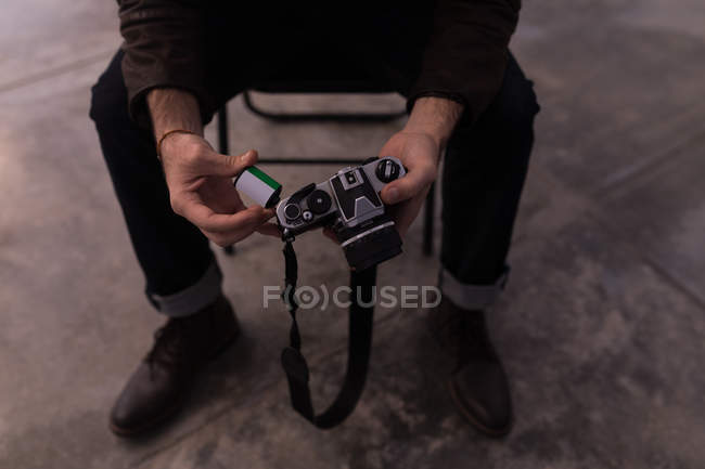 Male photographer holding roll film and camera in photo studio — Stock Photo