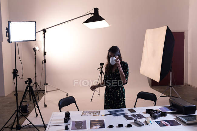 Femme photographe prenant un café tout en regardant des photos en studio photo — Photo de stock