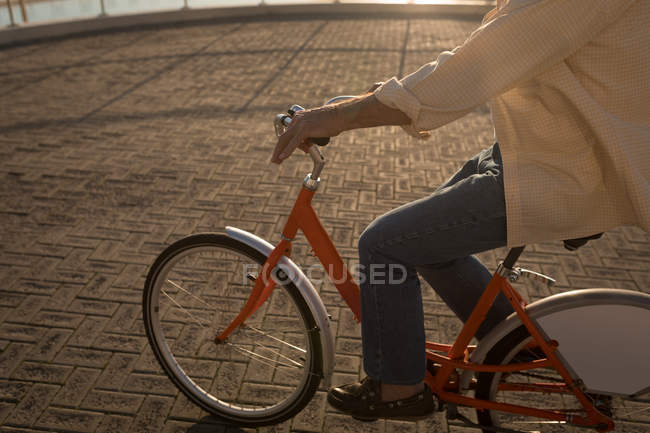 Seniorin fährt mit Fahrrad an Promenade — Stockfoto