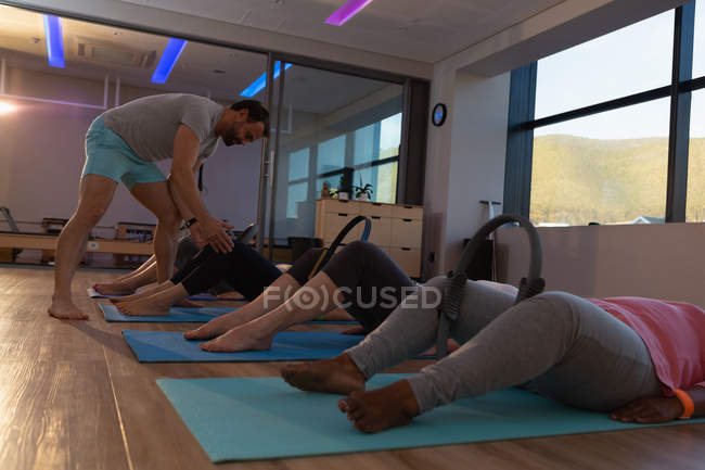Trainer assisting senior women in performing yoga at yoga center — Stock Photo