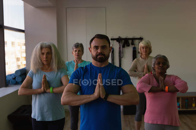 Entraîneur et groupe de femmes âgées effectuant du yoga dans le centre de yoga — Photo de stock