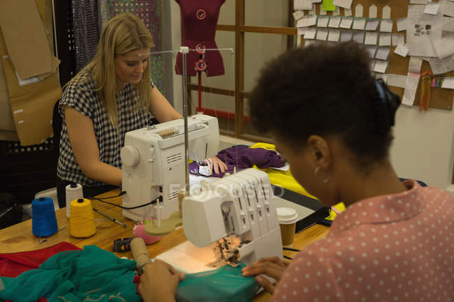 Designers de moda usando máquina de costura no estúdio de moda — Fotografia de Stock