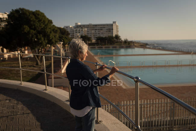 Mujer mayor parada en el paseo marítimo en un día soleado - foto de stock
