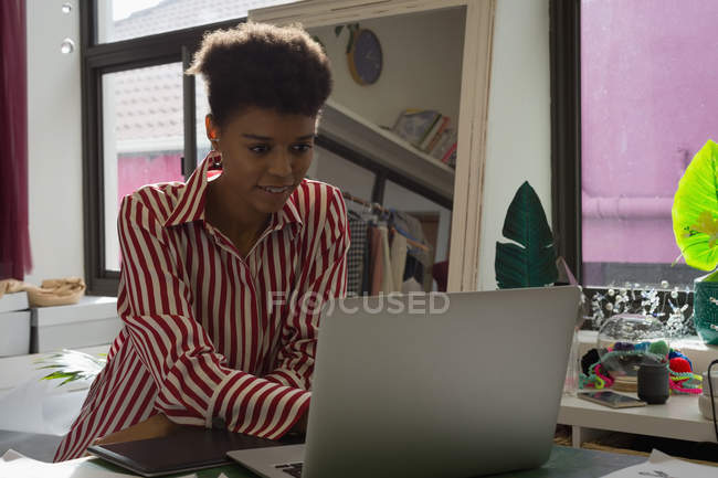 Fashion designer using laptop on desk in fashion studio — Stock Photo