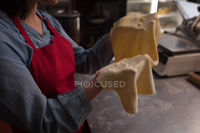Baker tenant une pâte roulée dans une main dans la boulangerie — Photo de stock