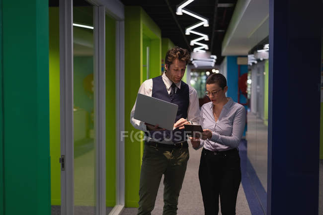 Коллеги по бизнесу обсуждают за цифровым планшетом в офисе — стоковое фото