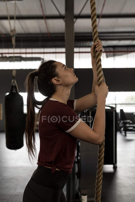Young woman doing rope climbing exercise in fitness gym — Stock Photo