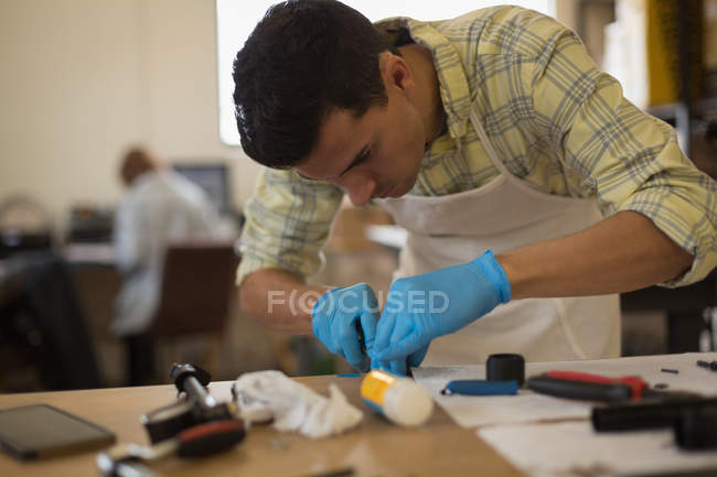 Attentive man cleaning bicycle parts on counter in workshop — Stock Photo