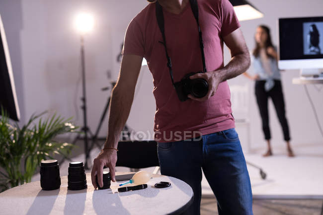 Photographe masculin changeant d'objectif de caméra en studio photo — Photo de stock